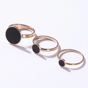 Detailed view of three stackable rose gold stainless steel rings with black disc elements