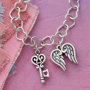 Detailed shot of silver heart-link bracelet with vintage key and wing pendants