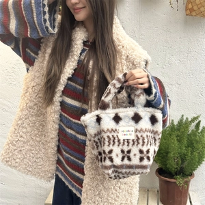 Close-up of soft beige plush handbag with blue and brown geometric jacquard patterns