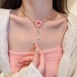 Detail of pink flower pendant necklace with beads, pearls and metal tassels on model