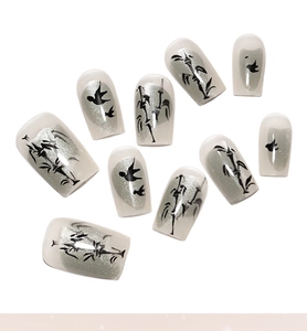 Detail of silver cat-eye press-on nails featuring black ink-wash bamboo and bird art