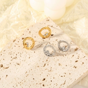 Detail of hammered stainless steel earrings with zircon stones in gold and silver