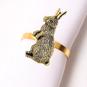 Close-up of a golden metal rabbit napkin ring on white linen for Thanksgiving table decor