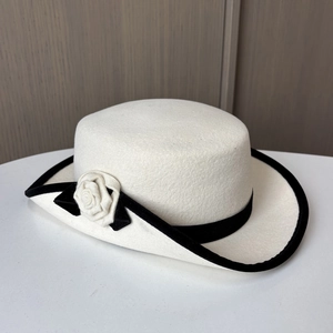 Détail d'un chapeau en feutre de laine crème avec bordure en velours noir et fleur en tissu