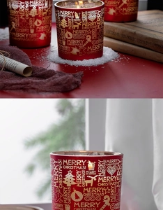 Detailansicht der roten Weihnachtskerze aus Glas mit goldener Aufschrift und Festdekoration