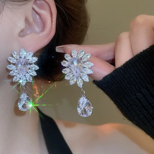 Close-up of sparkling zircon flower earrings with teardrop pendants on a model