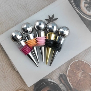 Detail of five-piece disco ball wine stoppers with colorful silicone rings on white board