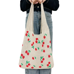 Off-white knitted cherry pattern tote bag held by a model on a white background