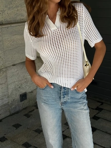 Detail of white hollow-out knit polo shirt featuring geometric cutout texture and v-neck