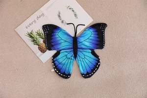 Detailed texture of a blue and purple gradient butterfly plush shell on a cozy carpet