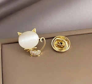 Macro shot of cat brooch with white opal stone and sparkling rhinestones on gold metal
