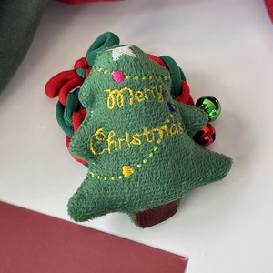 Détail d'un chouchou sapin de Noël en peluche verte avec broderie et petites clochettes