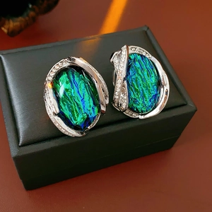 Close-up of vintage resin earrings with green and blue stones and sparkling rhinestones