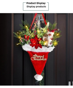 Close-up of lighted Santa hat door hanger with green pine needles and gold Merry Christmas sign