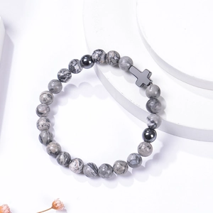 Detail view of 8mm pink zebra stone beads with black cross charm on a white stand