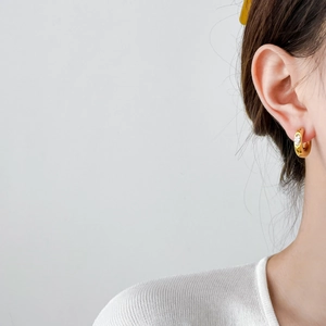 Detailed view of a gold-plated hoop earring with a sparkling cubic zirconia on model