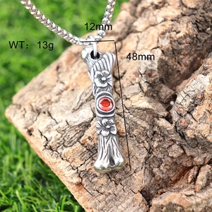 Macro view of vintage stainless steel bone pendant with red eye on aged wood surface