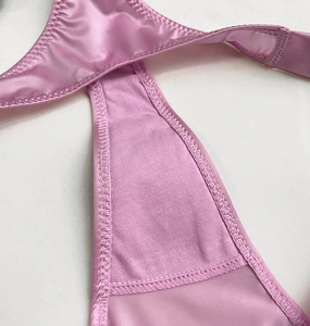 Detailed macro view of pink satin fabric texture and cross strap design with fine stitching