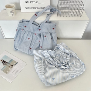 Detailed view of striped canvas tote bags with drawstring closure and bow patterns