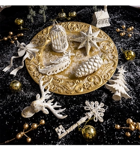 Detailed view of silver and white Christmas ornaments on a gold tray with a dark background