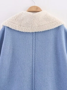 Detail of light blue denim jacket back with white faux shearling collar on wooden hanger