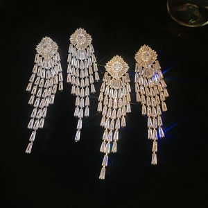 Macro shot of silver rhombic tassel earrings with glittering cubic zirconia on black background