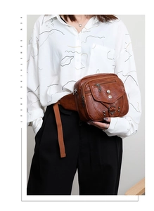 Détail d'un sac bandoulière vintage en cuir marron avec poches zippées porté par un mannequin