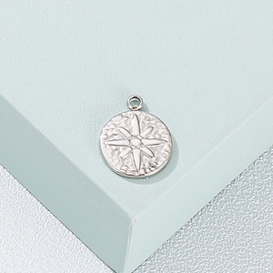Silver stainless steel round pendant with embossed star pattern on a display block