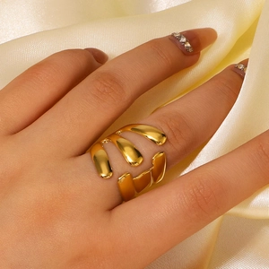 Bague dorée asymétrique au design fluide portée par un mannequin sur fond de soie élégante