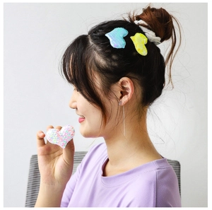 Détail de pinces à cheveux coeur à paillettes colorées et chouchou sur modèle