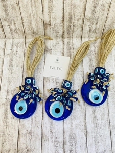 Close-up of three handmade glass Turkish evil eye charms with rustic jute rope hanging loops