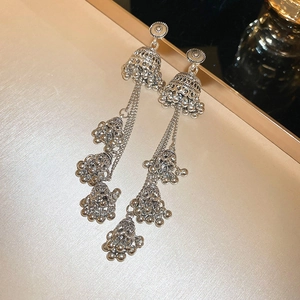 Macro detail of vintage silver Jhumka earrings with ornate bell tassels and metal finish