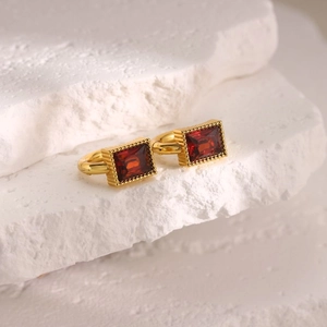 Macro detail of rectangle red zircon earrings with 18K gold plating on textured stone