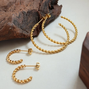 Golden twisted rope hoop earring set with two pairs of metal earrings on wooden base