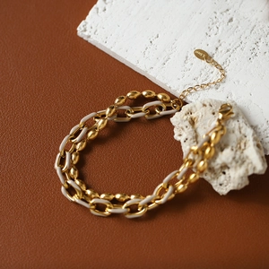 Détail d'un bracelet double chaîne doré avec gravure S.Steel sur cuir rouge