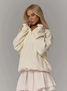 Détail du sweat à demi-zip crème montrant le coton doux et les poignets en maille côtelée