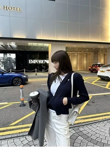 Detail of navy knit zip-up hoodie paired with white trousers and a minimalist shoulder bag