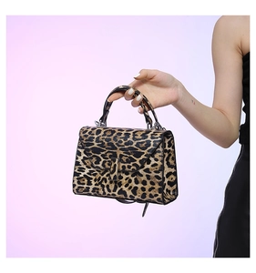 Detail of trendy leopard print handbag with a trapezoid shape and metallic lock buckle