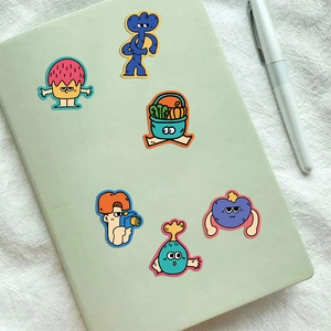 Detailed view of colorful cartoon stickers on a green notebook with a white pen