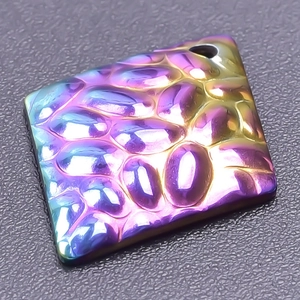 Macro shot of iridescent rainbow-plated square metal accessory with textured finish