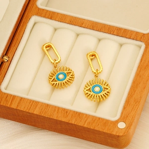 Boucles d'oreilles dorées avec œil bleu sur chaîne à maillons dans boîte en bois