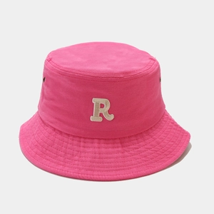 Close-up of the beige embroidered letter R on a rose red cotton fisherman bucket hat