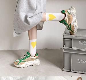 Close-up of a white and green chunky sneaker paired with high cotton heart socks