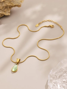 Détail du pendentif goutte verte sur collier à chaîne serpent en acier doré