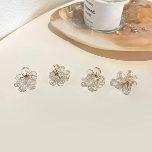 Detailed macro view of four small clear floral hair claws arranged on a beige table