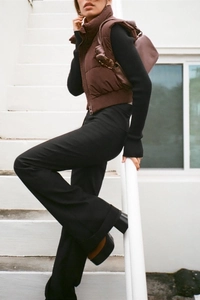 Outdoor street style view of a woman wearing a trendy brown cropped puffer vest
