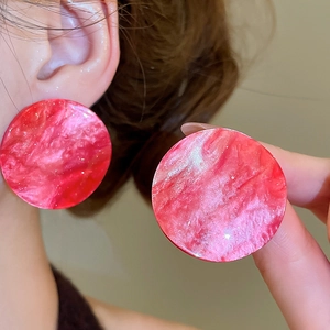 Macro detail of large red marble acrylic round earrings with unique swirl texture