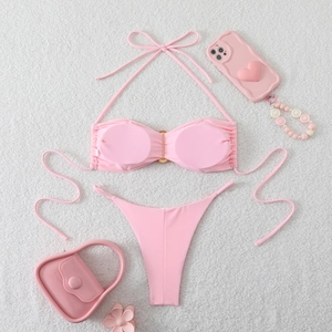 Detailed flat lay of pink bikini set with halter top and metal ring on white rug