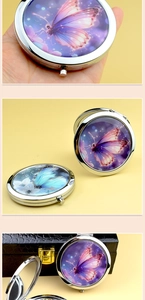 Detailed close-up of portable metal makeup mirror with elegant purple butterfly patterns