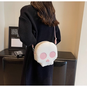 Detailed view of skull-shaped crossbody bag featuring pink heart eyes on white leather